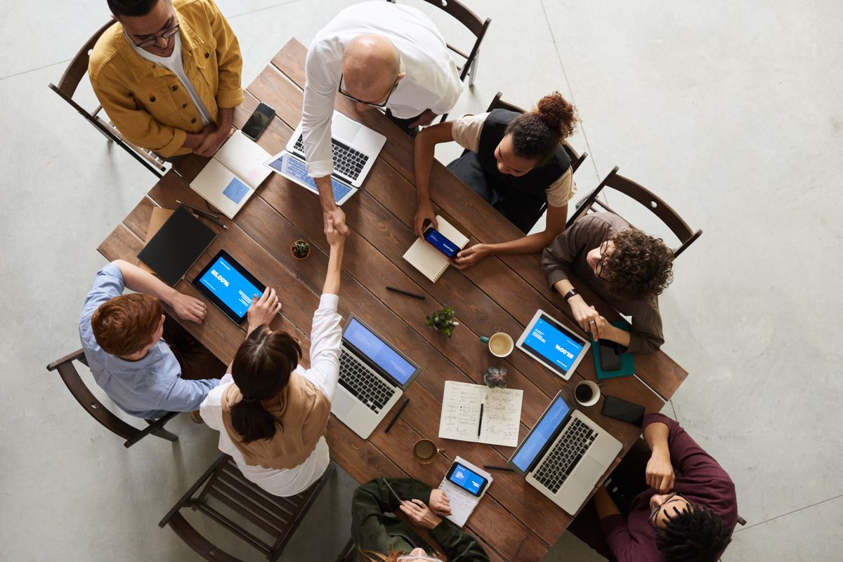 Small team review at the meeting table with proofs and notebooks